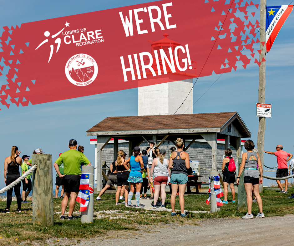 A group of people gathered in front of the Cape St. Mary's lighthouse before the Cape-to-Cliff beach run with the text 