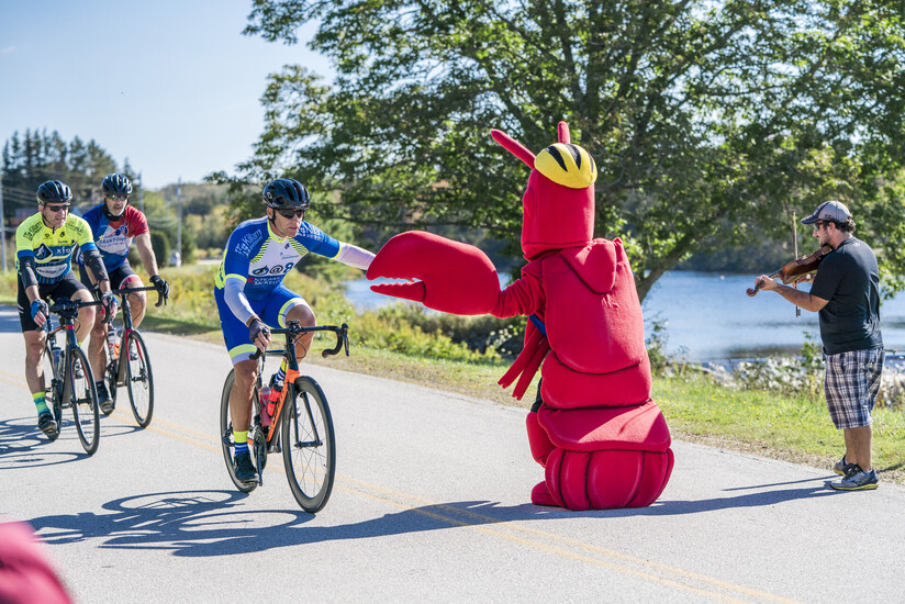 La mascotte du homard fait un high five à un cycliste